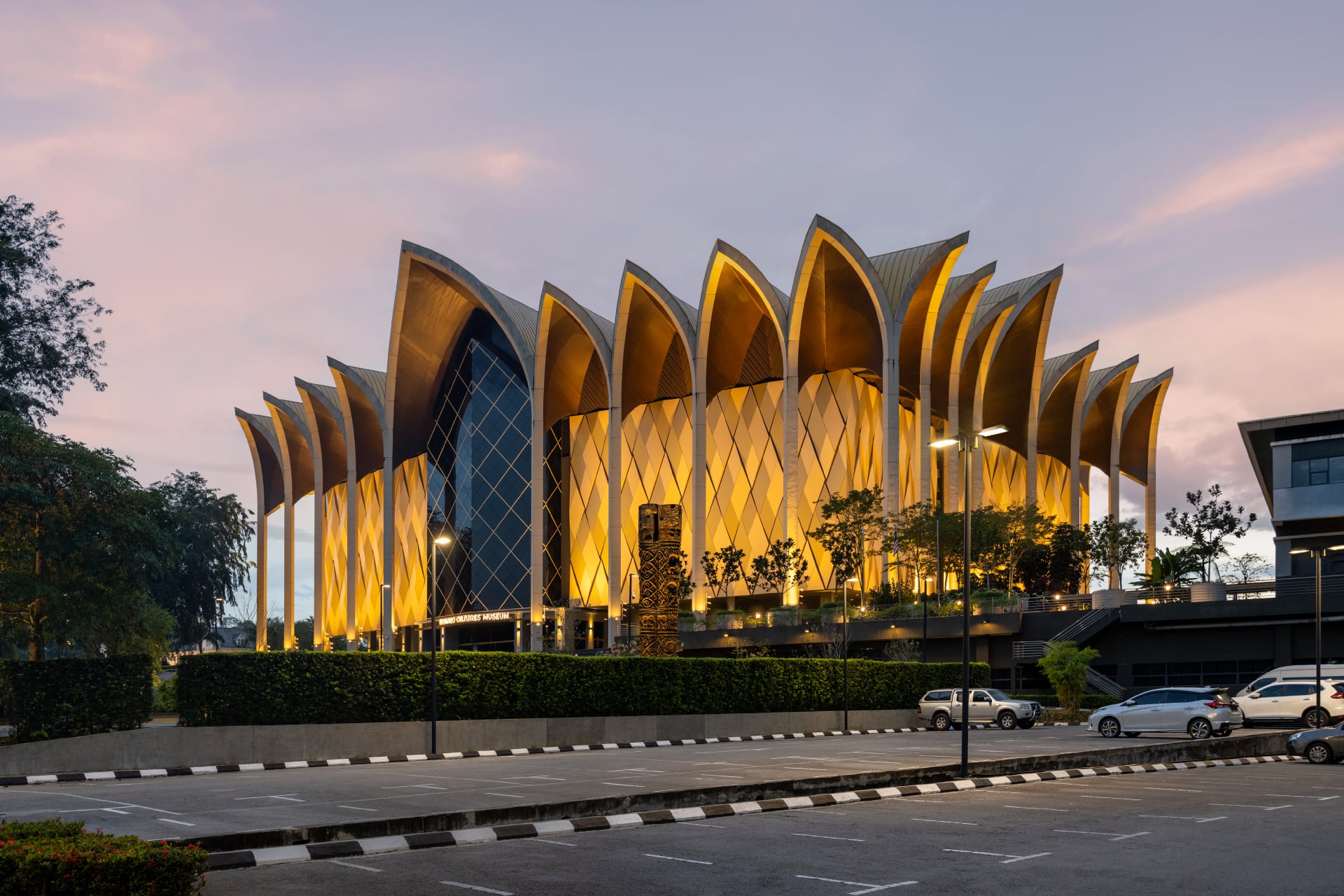 Evening view of the Borneo Cultures Museum in Malaysia with illuminated façade and atmospheric outdoor lighting.