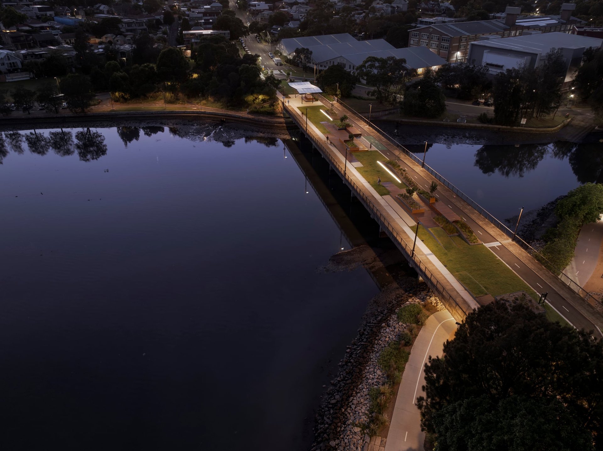 Aerial view of Bay Run showing a pedestrian and bicycle bridge crossing the water, with evening light and WE-EF street luminaires creating a calm, safe atmosphere.