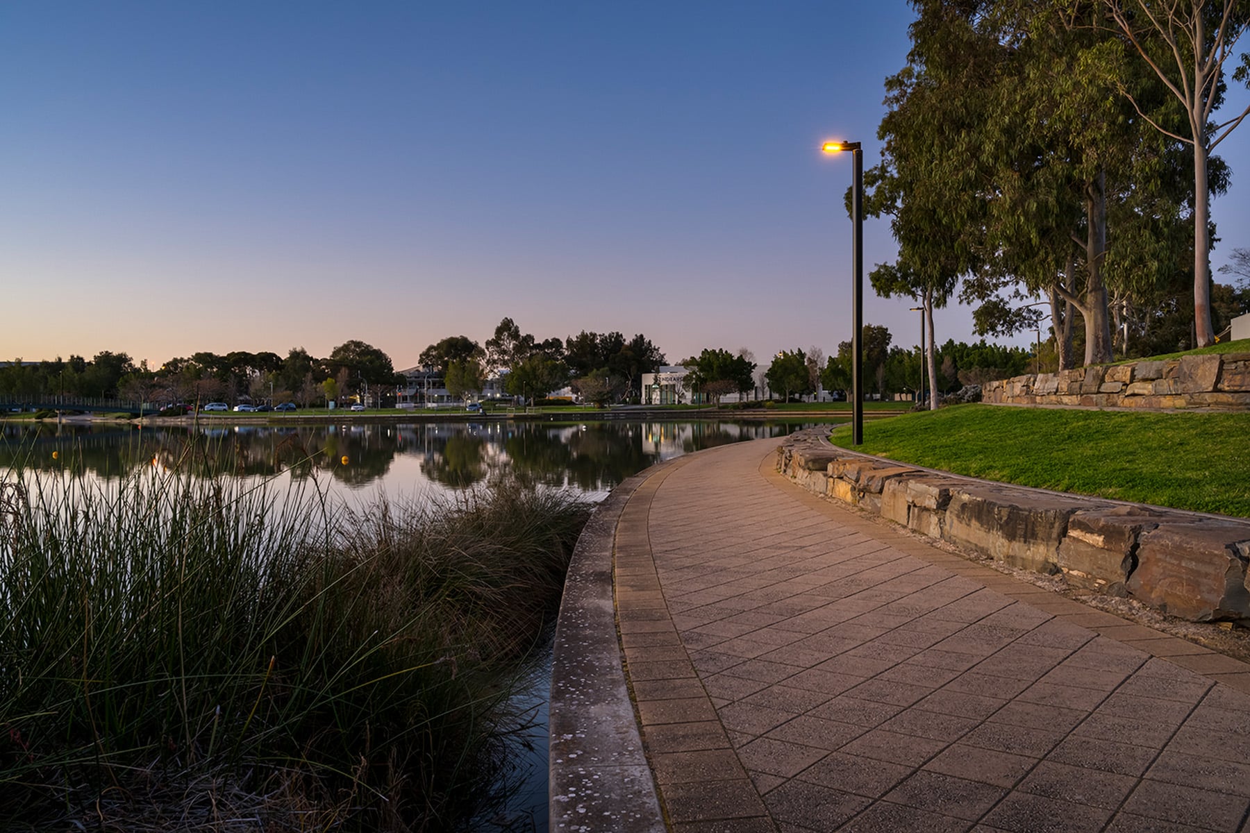 Luminaire along riverbank at dusk, illuminating pathway with WE-EF's Wild-Light technology to protect wildlife and promote sustainable outdoor lighting.