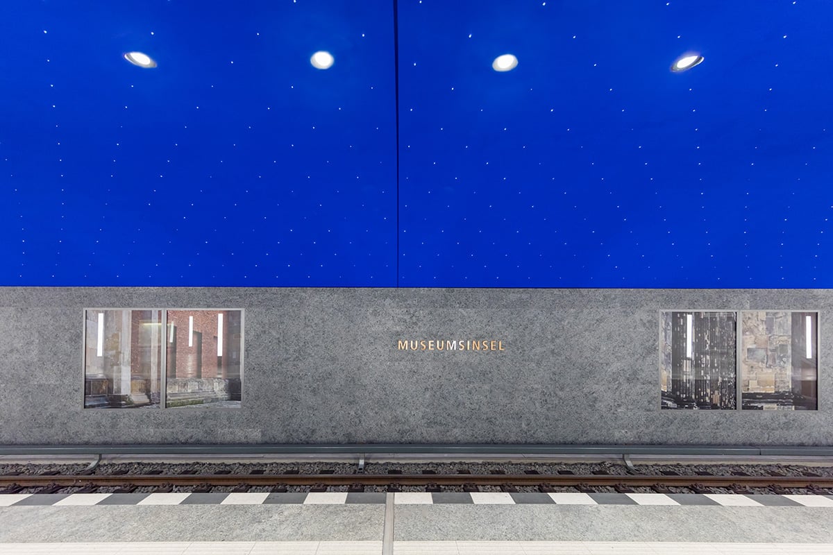 Close-up of WE-EF DOC220 recessed ceiling downlight with dark light optics and wide beam distribution providing glare-free platform lighting in Museumsinsel station's spectacular ultramarine blue arched vault adorned with 6,662 brilliant points of light creating starry sky effect inspired by Karl Friedrich Schinkel's 1816 Magic Flute stage set, recessed housing with special fitting ring enabling vertical installation in steel and plasterboard ceiling structure despite asymmetrical position