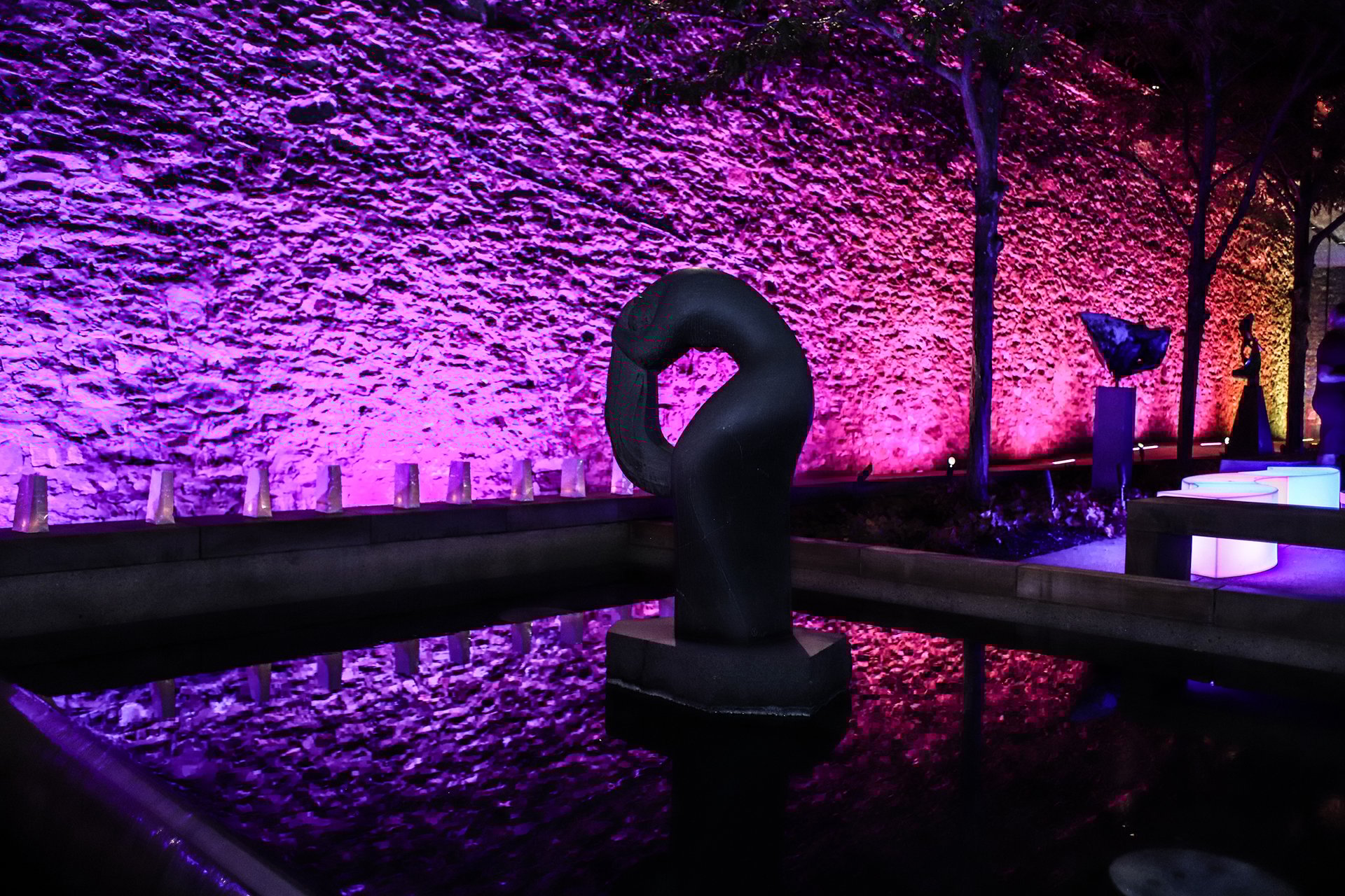 Museum sculpture garden, back wall is lit in pink